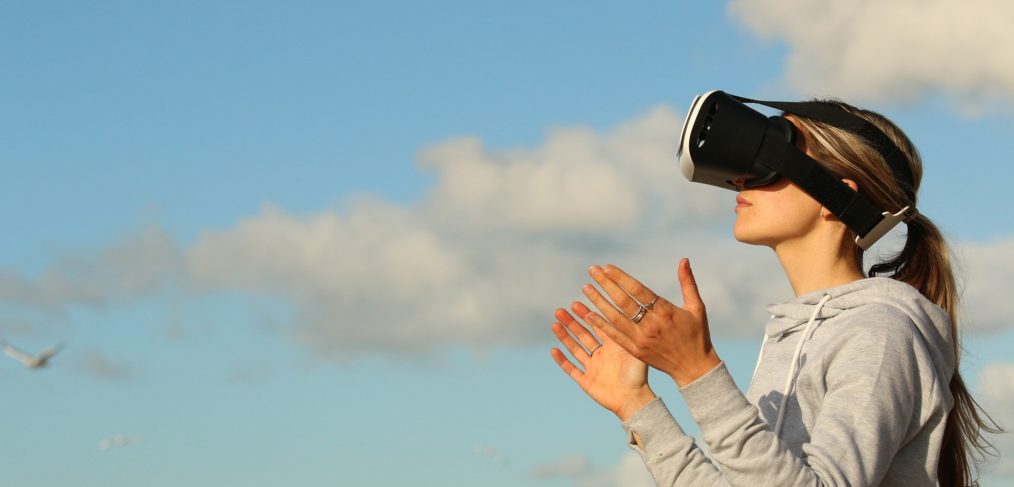 Frau trägt VR-Brille und hält die Hände hoch