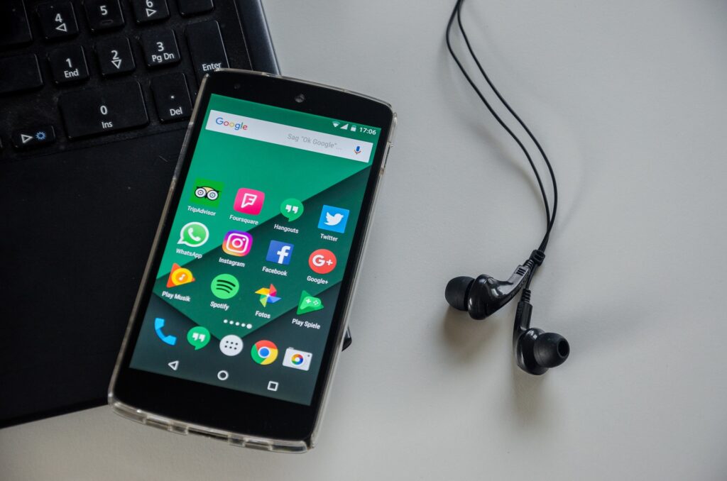 Foto: Ein Smartphone liegt auf einem Laptop. Daneben Kopfhörer.