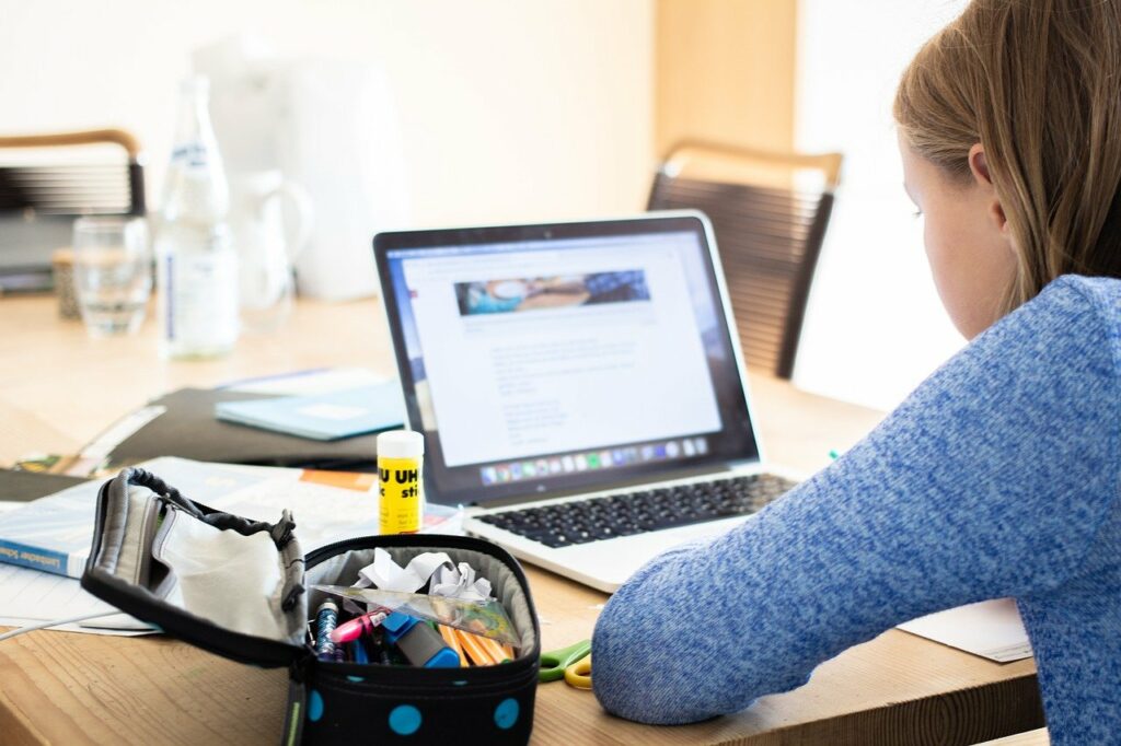 Foto: Ein Kind sitzt an einem Laptop und liest einen Text.