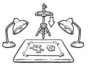 Legefilm Illustration in schwarz-weiß: Auf einem Tisch liegen zwei Bilder, neben dem Tisch stehen rechts und links Lampen, vor dem Tisch steht eine Kamera auf einem Stativ. Die Kamera filmt die zwei Motive auf dem Tisch von oben.